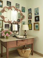 Display of framed paintings and mirror in hallway 