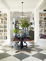 Circular table in centre of room with black and white checkered flooring 