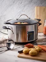 Slow cooker and vegetables on kitchen worktop 
