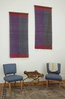 Chairs underneath two fabric wall hangings 