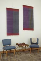 Chairs underneath two fabric wall hangings 