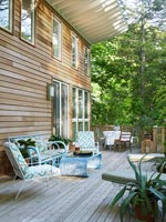 Furniture on decking of wooden house in woodland 