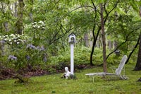 Bird table and recliner in woodland garden 
