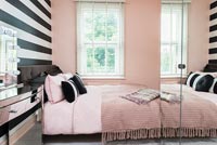 Pink bedroom with black and white striped wall  
