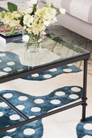 Glass coffee table on blue and white patterned rug 