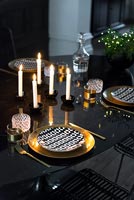 Gold crockery and cutlery on black dining table 