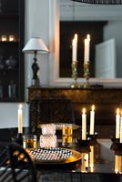 Gold crockery and cutlery on black dining table with candles 