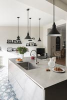 Modern kitchen with numerous pendant lights over island 