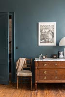 Classic chest of drawers and chair in bedroom with painted walls 