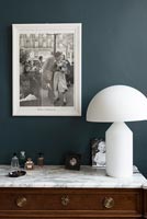 White modern lamp and photograph on chest of drawers with marble top