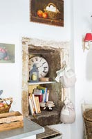 Stone alcove with recipe books on shelves in rustic kitchen 