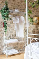 White metal clothes rail with natural garlands and exposed stone wall 