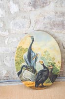 Oval painting of birds against exposed stone wall 