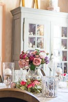 Roses in vintage glass vase on classic dining table 