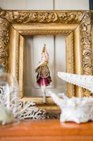 Figurine suspended inside gilded picture frame 