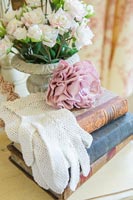 Lace gloves and vintage pink rose on pile of old books 