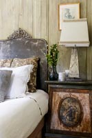 Velvet headboard in classic bedroom with ornate side table and lamp 