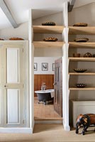 Shelves of ceramic bowls around doorway to en-suite bathroom 