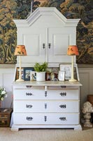 White painted bureau and patterned wallpaper 
