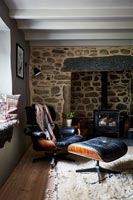 Designer chair and footstool next to fireplace in country living room 
