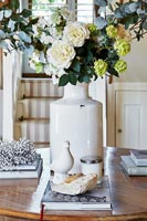 Large white vase of flowers on wooden table 