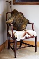 Furry cushion and animal skin on wooden armchair 