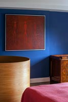 Red modern artwork on blue painted wall in bedroom 