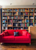 Wall of bookshelves and red sofa 