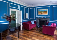 Azure blue painted living room with pink velvet sofas 