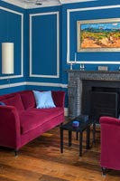 Azure blue painted walls and pink velvet sofas in classic living room 