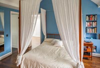 White four poster bed in blue and white bedroom 