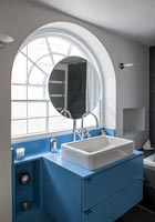 Blue and white bathroom with arched window 