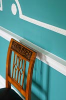 Antique chair next to blue painted wall with original mouldings 