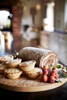 Yule log, mince pies and fruit on wooden board