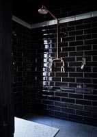 Shower with black brick style tiling and copper shower head 