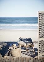 Wooden platform with bed and folding screen on beach 