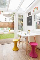 Colourful stools around small table in garden room 