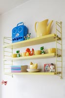 Yellow shelves with childrens toys and crockery 
