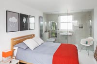 Modern bedroom with en-suite bathroom separated by glazed wall 