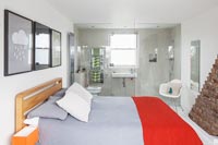 Modern bedroom with en-suite bathroom separated by glazed wall 