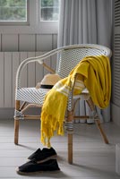 Yellow throw on white wicker chair 