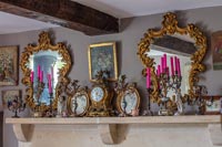 Candles, clocks and vintage mirrors on mantelpiece 