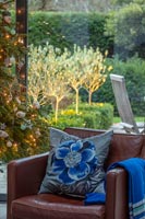 Embroidered blue floral cushion on leather armchair next to Christmas tree. 