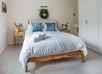 White bedroom with Christmas wreath above the bed 
