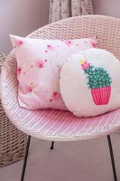 Modern patterned cushions on pink rattan chair 
