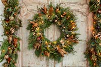 Christmas wreath and garland with fairy lights on double wooden doors 