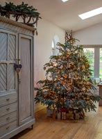 Christmas tree next to large grey painted cabinet