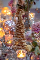Miniature gold Christmas tree and candles on dining table 