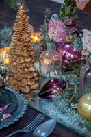 Miniature gold Christmas tree and decorations on dining table 