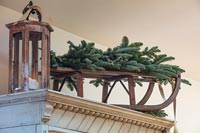 Sprigs of fir on wooden sledge on top of wardrobe with lantern 